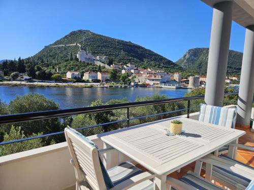 a table and chairs on a balcony with a view of a river at Apartment Waterfront Oasis-3 by Interhome in Mali Ston