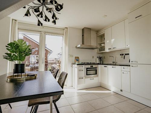 a kitchen with white cabinets and a table with a potted plant at Apartment Oostergeest 2 by Interhome in Uitgeest