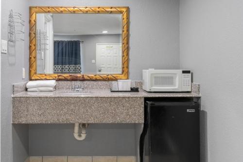 a bathroom with a sink with a microwave and a mirror at Golden Inn Dallas by Hotel O in Dallas