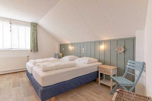 a bedroom with a large bed and a blue chair at Seinpost Appartment in Callantsoog