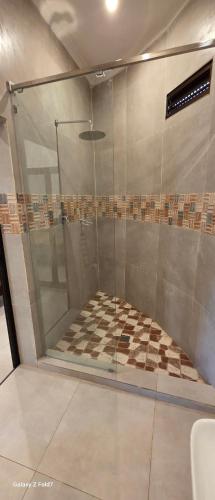 a glass shower with a checkered floor in a bathroom at Hotel Nhungue & Shopping Lda in Tete