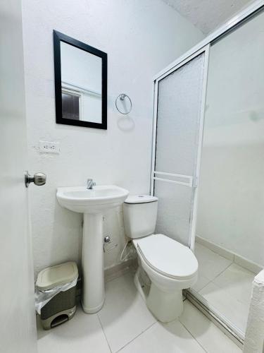a white bathroom with a toilet and a sink at Hotel Casa Manzanares in Santa Marta
