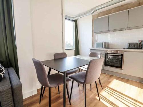 a kitchen with a table and chairs in a room at Woolston Central 2-Bedroom Apartment in Warrington