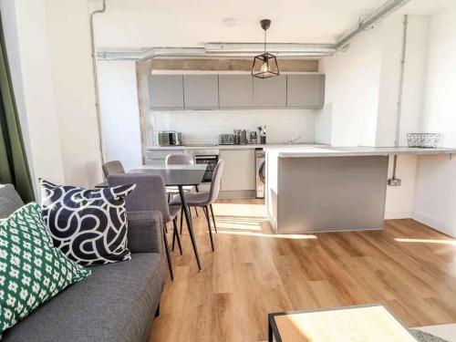 a living room with a couch and a table and a kitchen at Woolston Central 2-Bedroom Apartment in Warrington