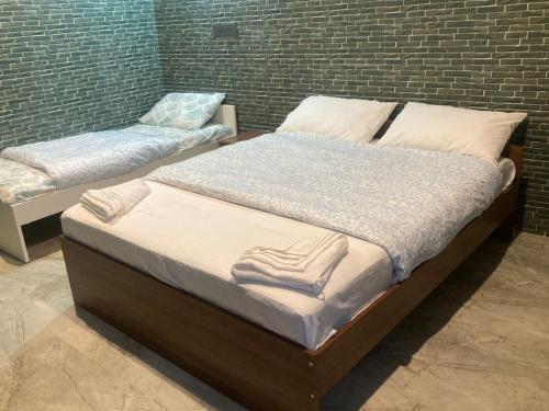 two twin beds in a room with a brick wall at Nature's Resort in Kaivār