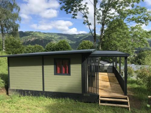 a tiny house with a porch and a deck at ZEcamping 4 étoiles animaux acceptés tennis piscine couverte in Vic-sur-Cère