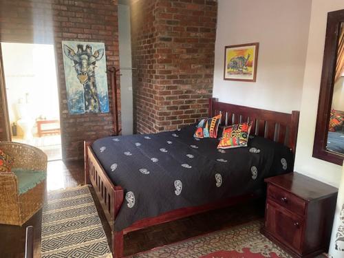 a bed in a bedroom with a brick wall at Sunshine Guest House in Harare