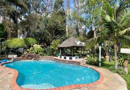 a swimming pool in a yard with a gazebo at Sunshine Guest House in Harare
