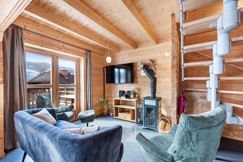 a living room with a couch and chairs and a fireplace at Alpen Chalets Ausseerland - Sauna & BBQ in Bad Mitterndorf