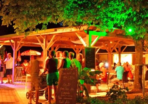 a group of people standing outside a restaurant at night at Camping La Clairière - Aquatique Vacances in Saint-Paul-en-Born