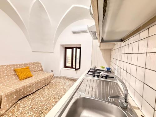 a kitchen with a sink and a couch in a room at Scorcio Sul Mare in Gallipoli
