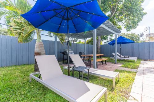 a patio with chairs and a blue umbrella at Hollywood Villa Luxury & Private Pool in Hollywood