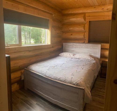 a bed in a log cabin with a window at Cougar Mountain Lodge and Resort Cabin Rentals in Valemount