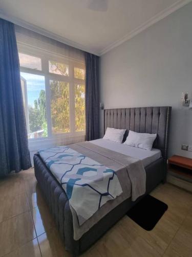 a bedroom with a large bed with a large window at Legacy Homes in Dar es Salaam