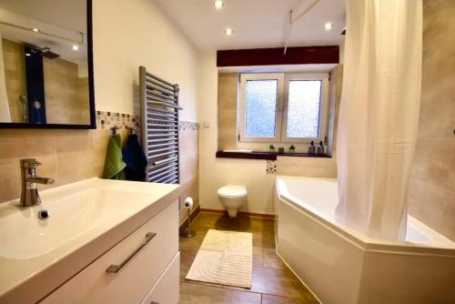 a bathroom with a tub and a sink and a toilet at Fewo Eifel Dahlem Nationalpark Sonnenterrasse & Kamin in Dahlem