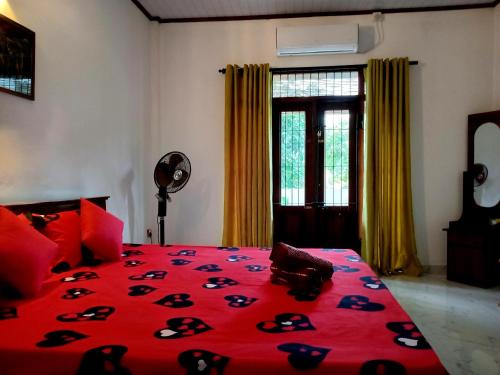 a bedroom with a bed with a red comforter at Villa Keturah in Katunayaka
