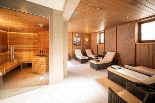 a room with a sauna with a couch and chairs at Familienhotel Lengauer Hof in Saalbach-Hinterglemm