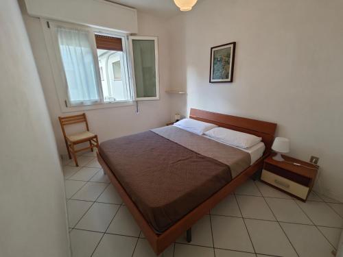 a bedroom with a bed and a chair and a window at Residence Sporting in Rosolina Mare