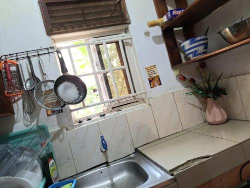 a kitchen with a sink and a frying pan on a window at Homey Stay in Kampala