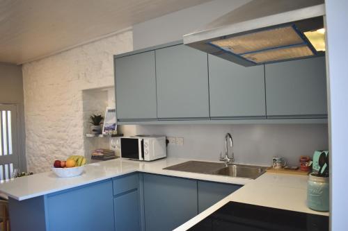 a kitchen with blue cabinets and a bowl of fruit at Sunday Cottage in St. Just