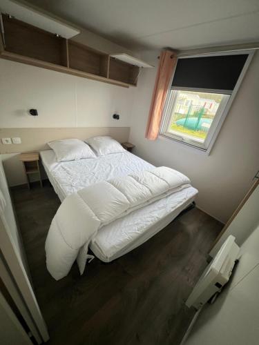 a large white bed in a room with a window at Mobil Home Litteau Calvados in Litteau