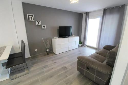 a living room with a couch and a television at Cozy Apartment in Vinaròs with Shared Pool in Vinarós