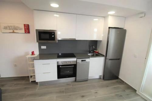 a kitchen with white cabinets and a stainless steel refrigerator at Cozy Apartment in Vinaròs with Shared Pool in Vinarós