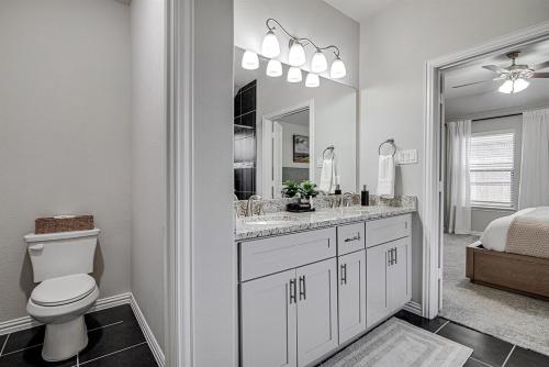 a bathroom with a toilet and a sink and a mirror at Where Comfort Meets Convenience in Burleson