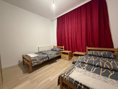 a room with two beds and a red curtain at Cozy Apartment in Prishtinë