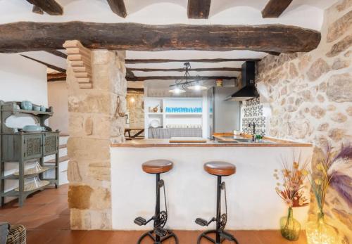 a kitchen with two stools at a counter in a stone building at La Casuna de la Una in Olba