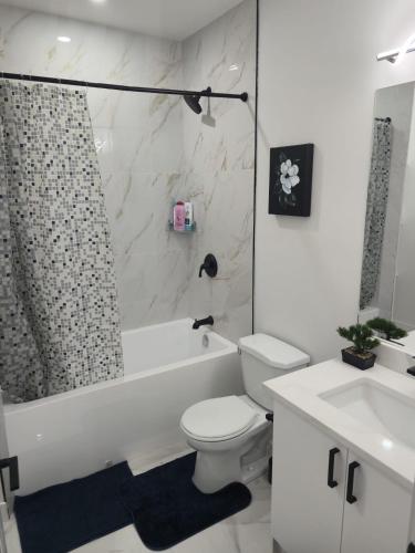 a bathroom with a toilet and a tub and a sink at Mayfair Suite in Airdrie