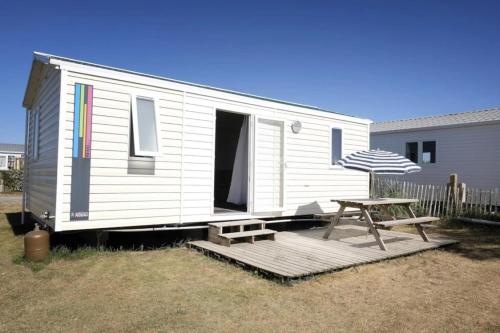 a white tiny house with a picnic table and an umbrella at ZEcamping 3 étoiles piscine chauffée club enfant dog friendly in Ploemeur
