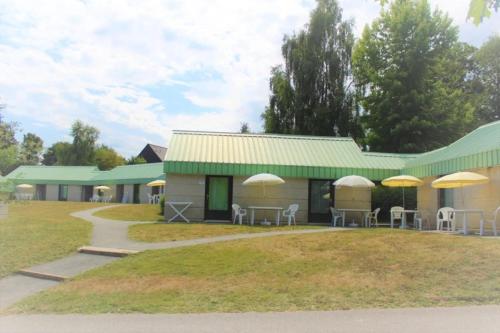 a building with tables and chairs and umbrellas at ZEcamping 3 étoiles pet friendly animations piscine chauffée in Merdrignac
