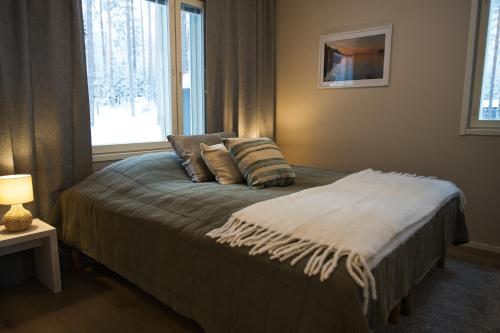 a bedroom with a bed with pillows and a window at Villa Mustikkaranta Koli, oma ranta in Kolinkylä