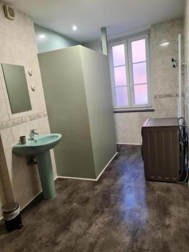 a bathroom with a green sink and a window at Le haut clocher in Fumay