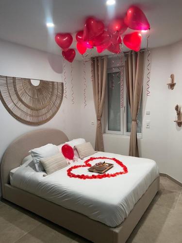 a bed with red balloons and a cake on it at Jardin eden88 in Saint Die