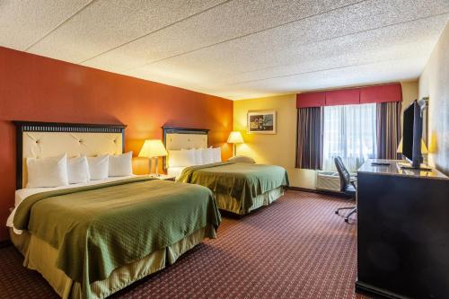 a hotel room with two beds and a flat screen tv at Quality Inn & Suites Lincoln South in Lincoln