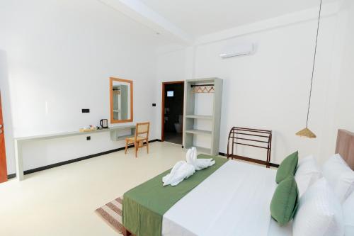 a white bedroom with a bed and a desk at KIRI's HEAVEN in Ahangama