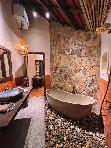 a stone bathroom with a tub and a stone wall at Tam Coc Thoms House in Ninh Binh