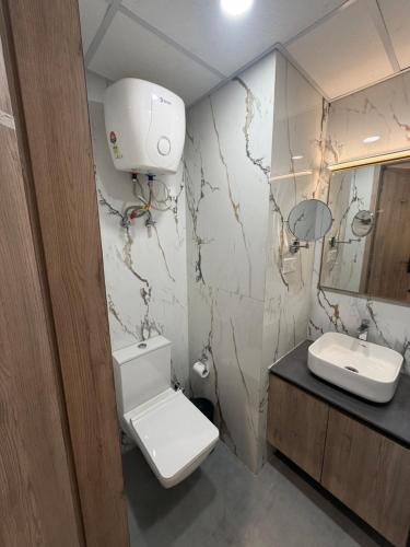 a bathroom with a toilet and a sink at The Sterling Aroma in Greater Noida