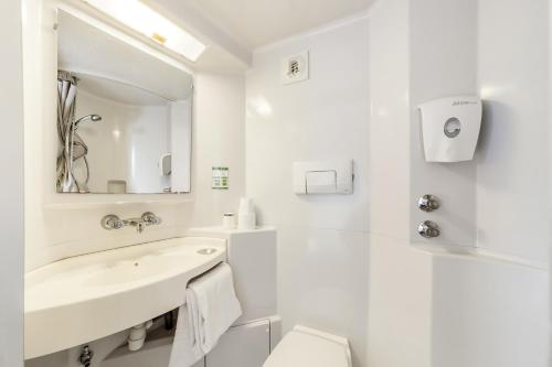 a white bathroom with a sink and a toilet at Mister Bed Chambray Les Tours in Chambray-lès-Tours