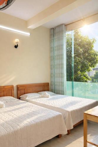 two beds in a bedroom with a large window at Tâm Quỳnh Motel in Vung Tau