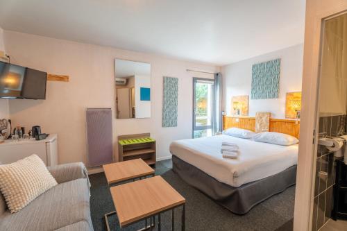 a hotel room with a bed and a couch at Escale Kennedy in Mérignac