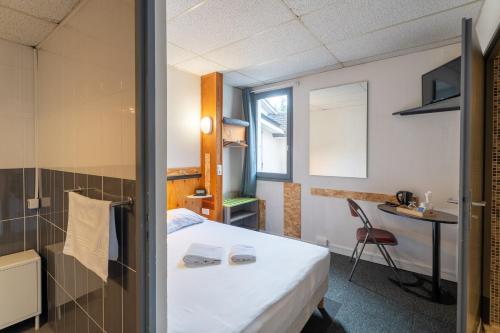 a hotel room with a bed and a desk at Escale Kennedy in Mérignac