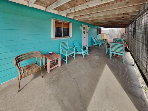 a patio with chairs and tables and a blue wall at Paradise Retreat in Port Aransas