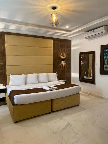 a bedroom with a large bed with a wooden headboard at Presken Hotel White House, Lekki, Lagos in Lagos