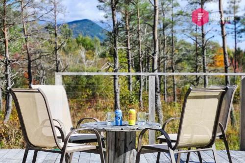 a table and chairs on a patio with a view of the forest at Le Pèlerin - Chalet rustique Écoresponsable en nature - Estrie in Notre-Dame-Des-Bois