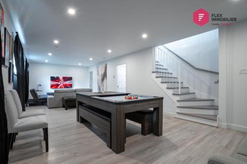 a living room with a ping pong table and stairs at La Casa Bella - Luxury, Comfort, Pool & private SPA in Valcartier Station