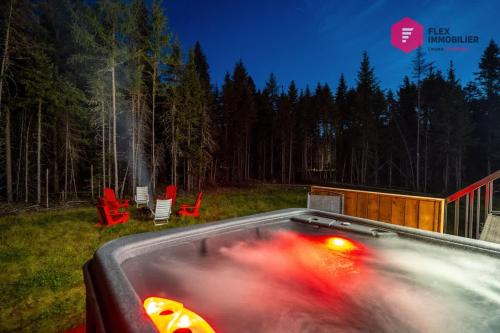 a hot tub in a yard with red chairs at La Casa Bella - Luxury, Comfort, Pool & private SPA in Valcartier Station