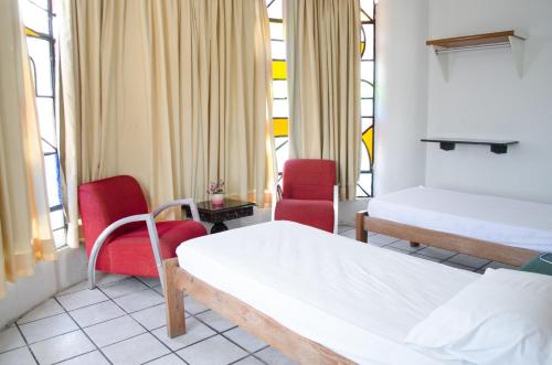 a room with two beds and two chairs and windows at Pousada Mucuripe in Fortaleza